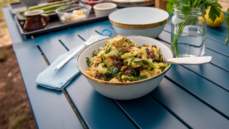 A bowl of curry chicken salad on a blue table