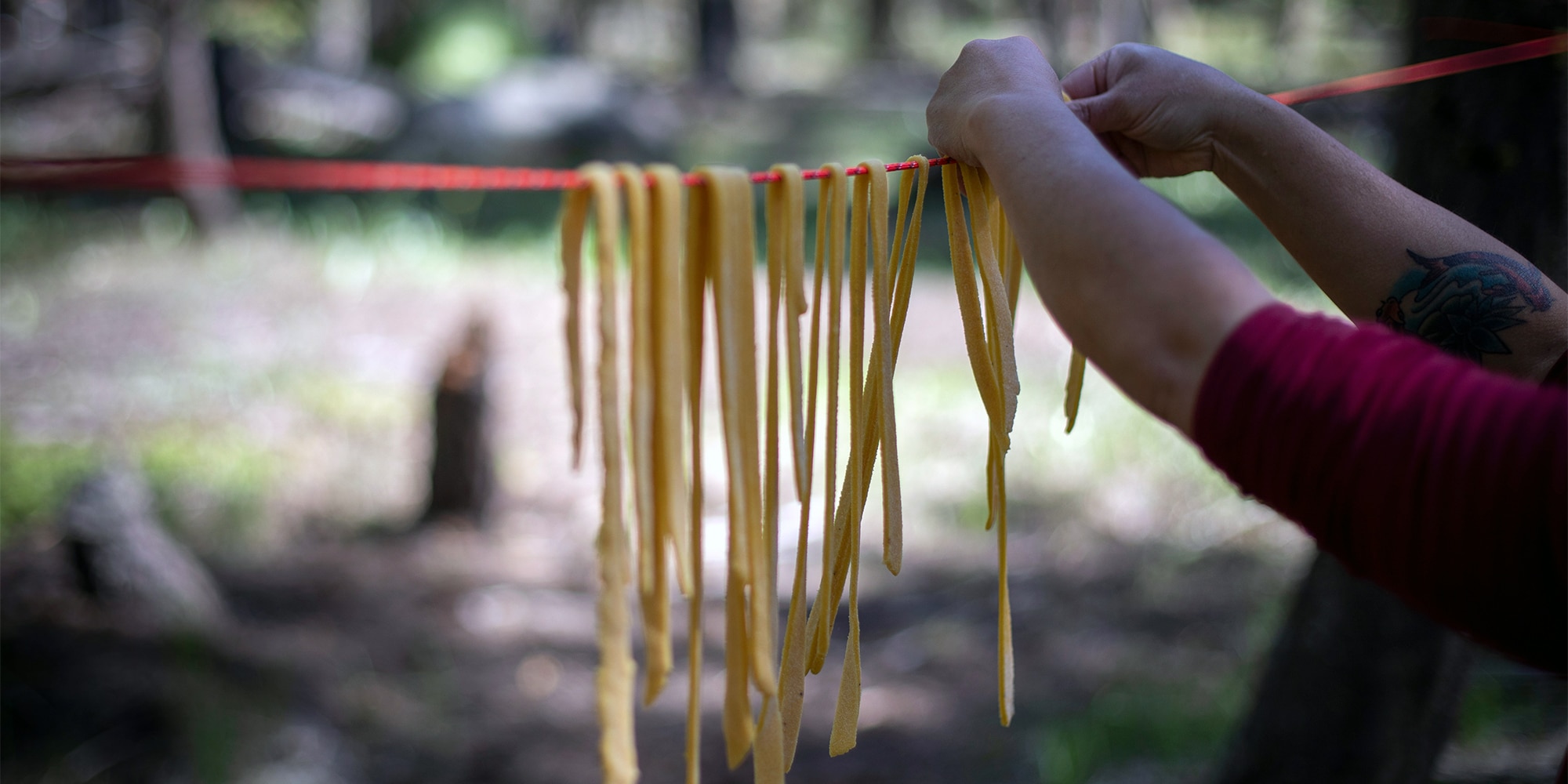 Maria Hines hangs raw pasta noodles from a rope.