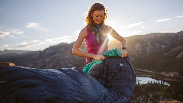camper opens sleeping bag at campsite