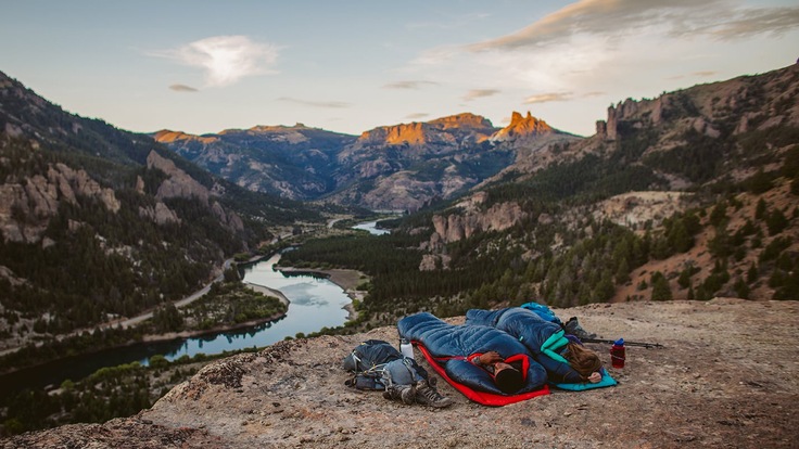 Two ultralight backpackers sleep in sleeping bags out in the open air