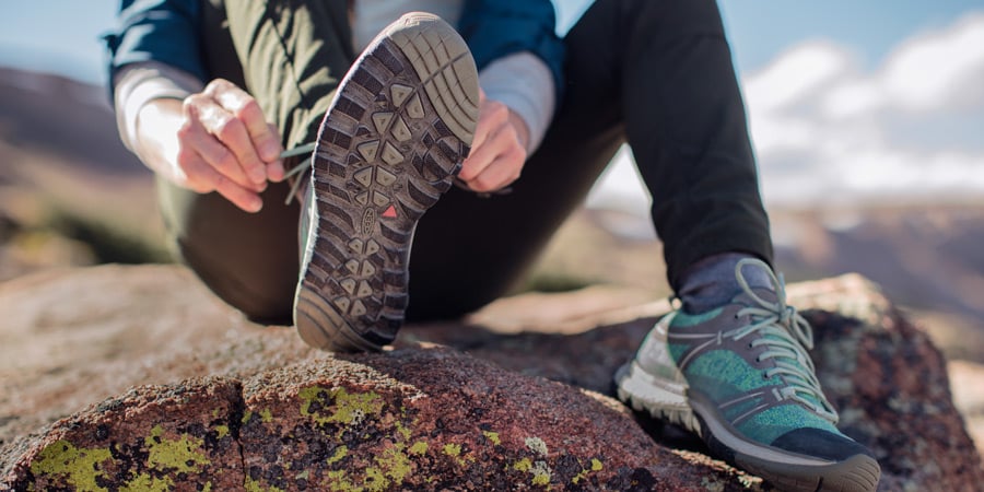 a hiker resting and adjusting their hiking boots while on the trail