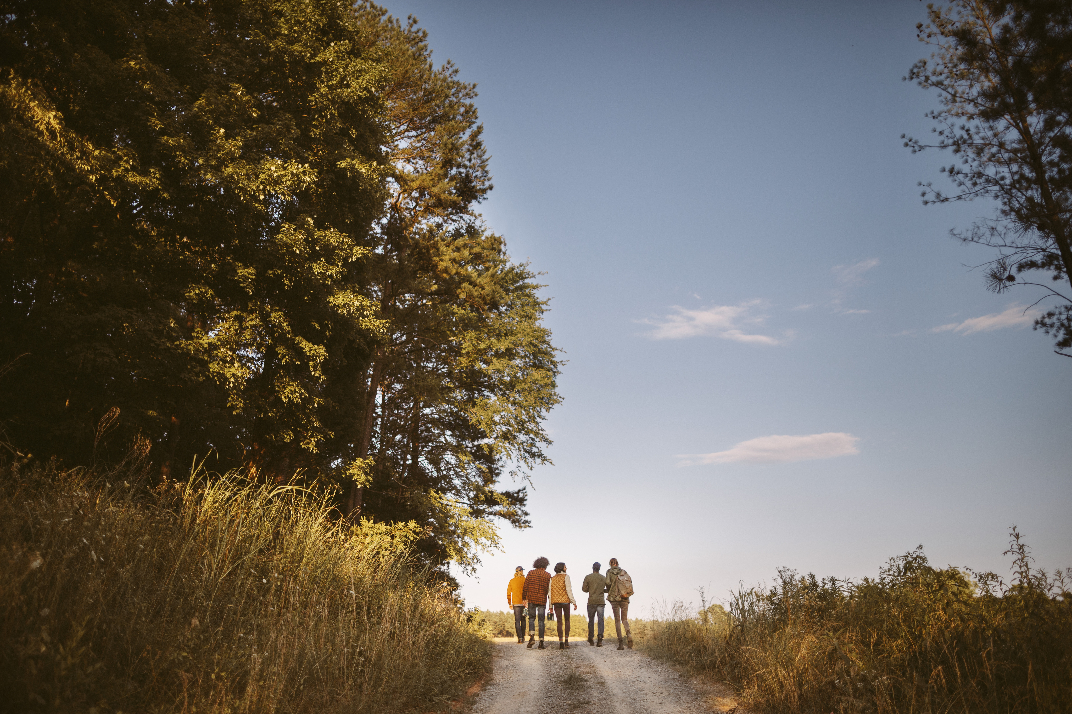 A group of friends walk down a dirt path