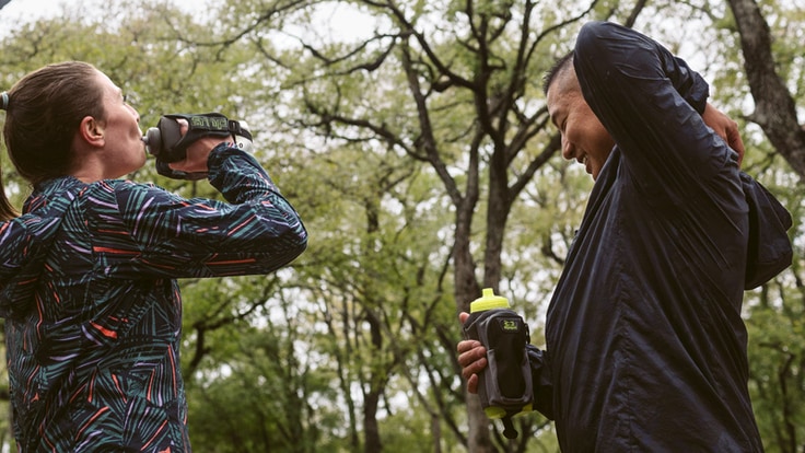 runners drinking water from handheld water bottles