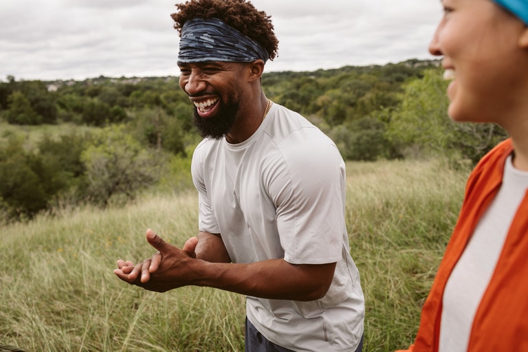 Man in running gear in a field laughing