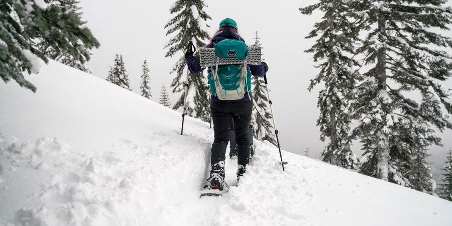 A woman traversing a slope while snowshoeing