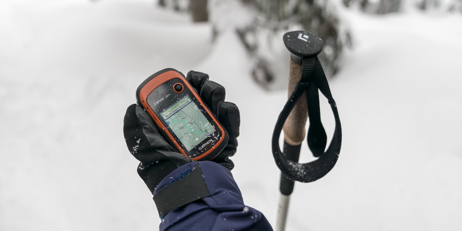 A snowshoer checks their location on a GPS device