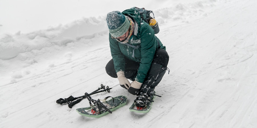 A woman putting on snowshoes