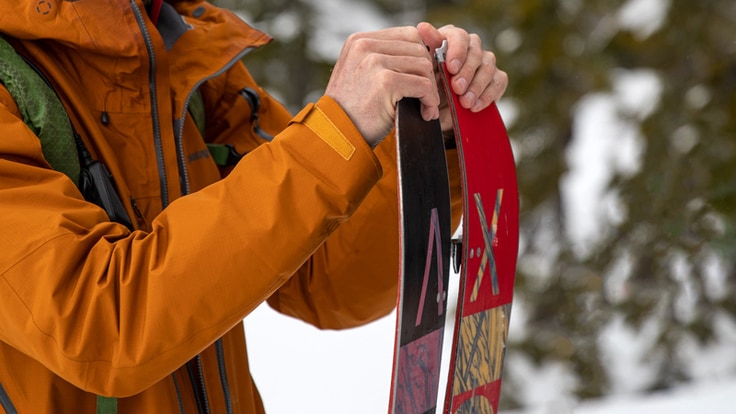 A snowboarder takes apart a splitboard to turn it into two skis