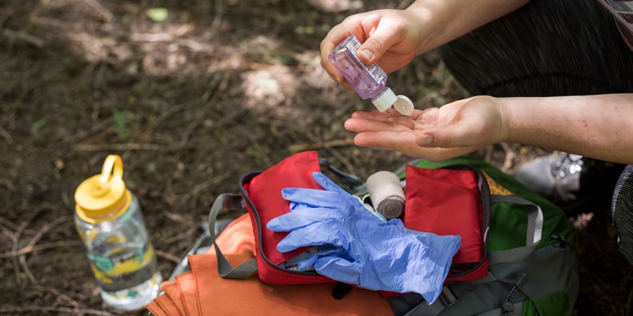 a wilderness first aid responder washing their hands and preparing to put on gloves before providing aid