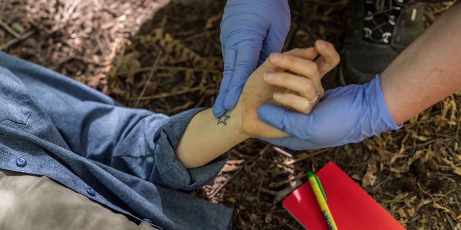 first aid responder checking for patient's wrist pulse