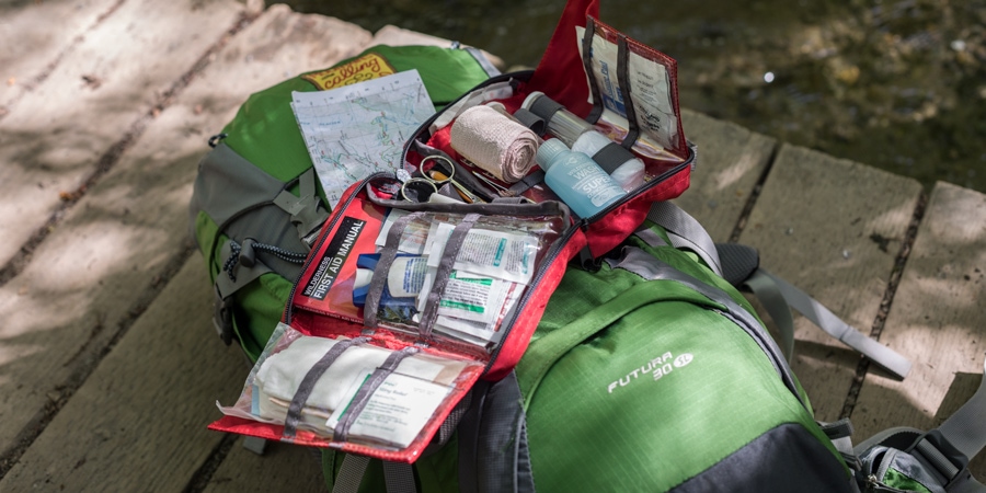 A first-aid kit lies open on top of a hiking pack