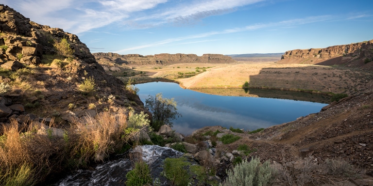 A river feeds into a desert lake under early morning light in Eastern Washington