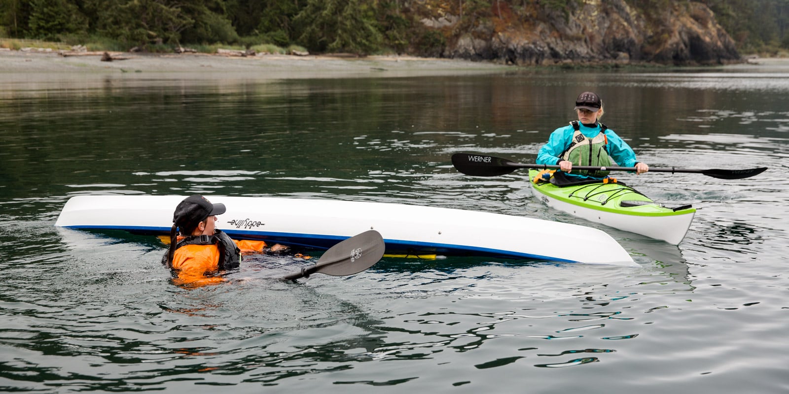 Instructor in the water with a flipped kayak as a student watches