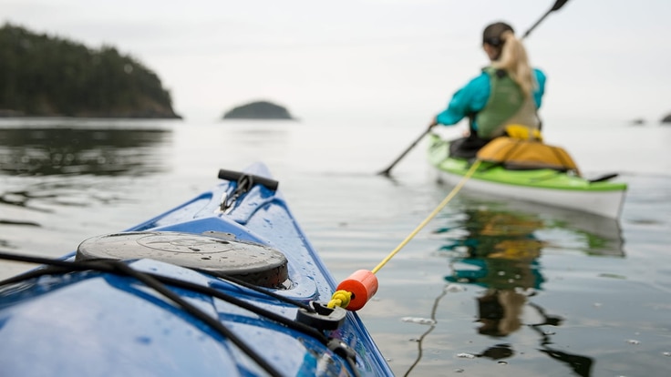 a kayaker being towed by another kayaker