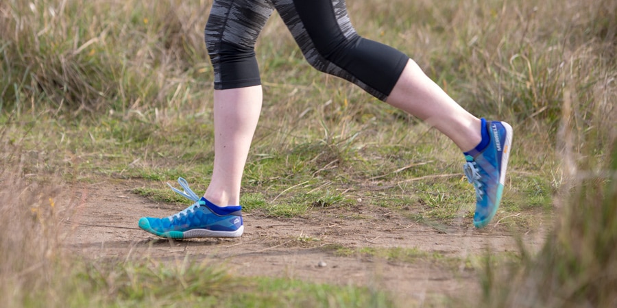 A runner on a trail lands on her midfoot