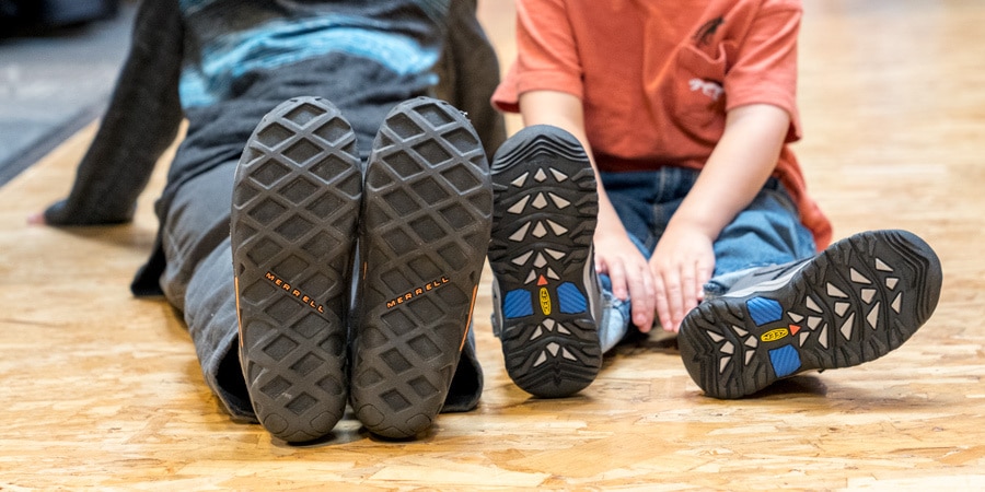 Kids sitting on floor and can see the treads of their shoes