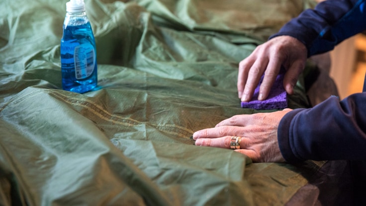 someone spot cleaning a dirty tent