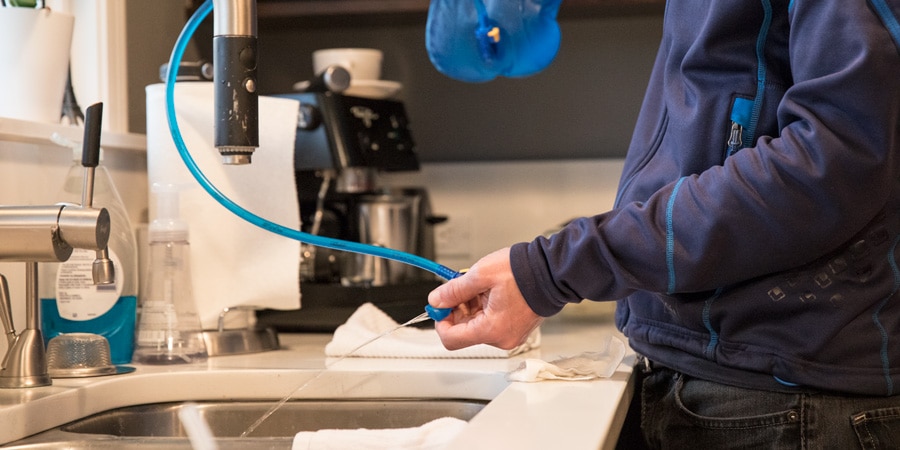 Pinching the bite valve of a hydration bladder to ensure that the cleaning solution reaches the tube