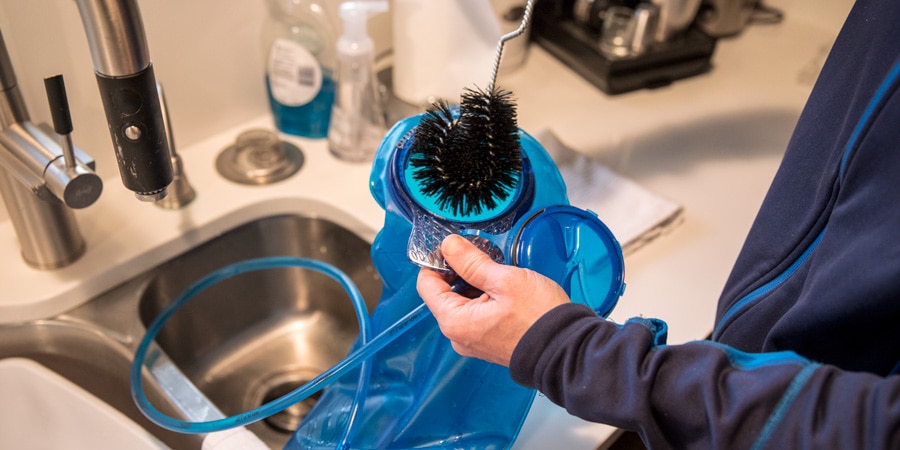 Scrubbing the inside of a hydration reservoir with a bristle brush