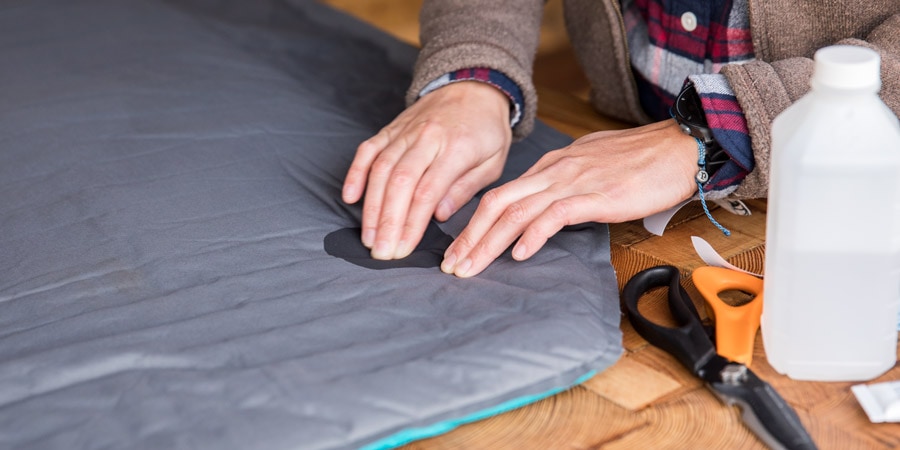 A woman applies a patch to a sleeping pad