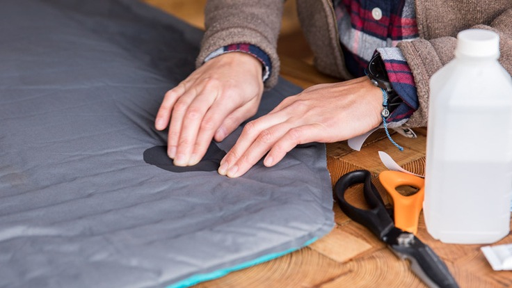 A woman applies a patch to a sleeping pad