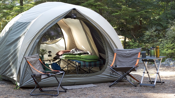 Picture of campsite setup with tent, cots, chairs and tables.