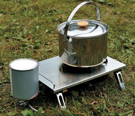 Durable camping stove in action, boiling water quickly with a vibrant flame, at a scenic lakeside campsite.
