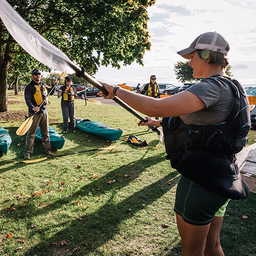 REI outdoor class instructor shows kayakers how to hold a paddle