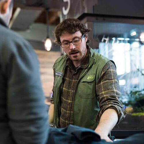 An REI employee in the store helps a customer